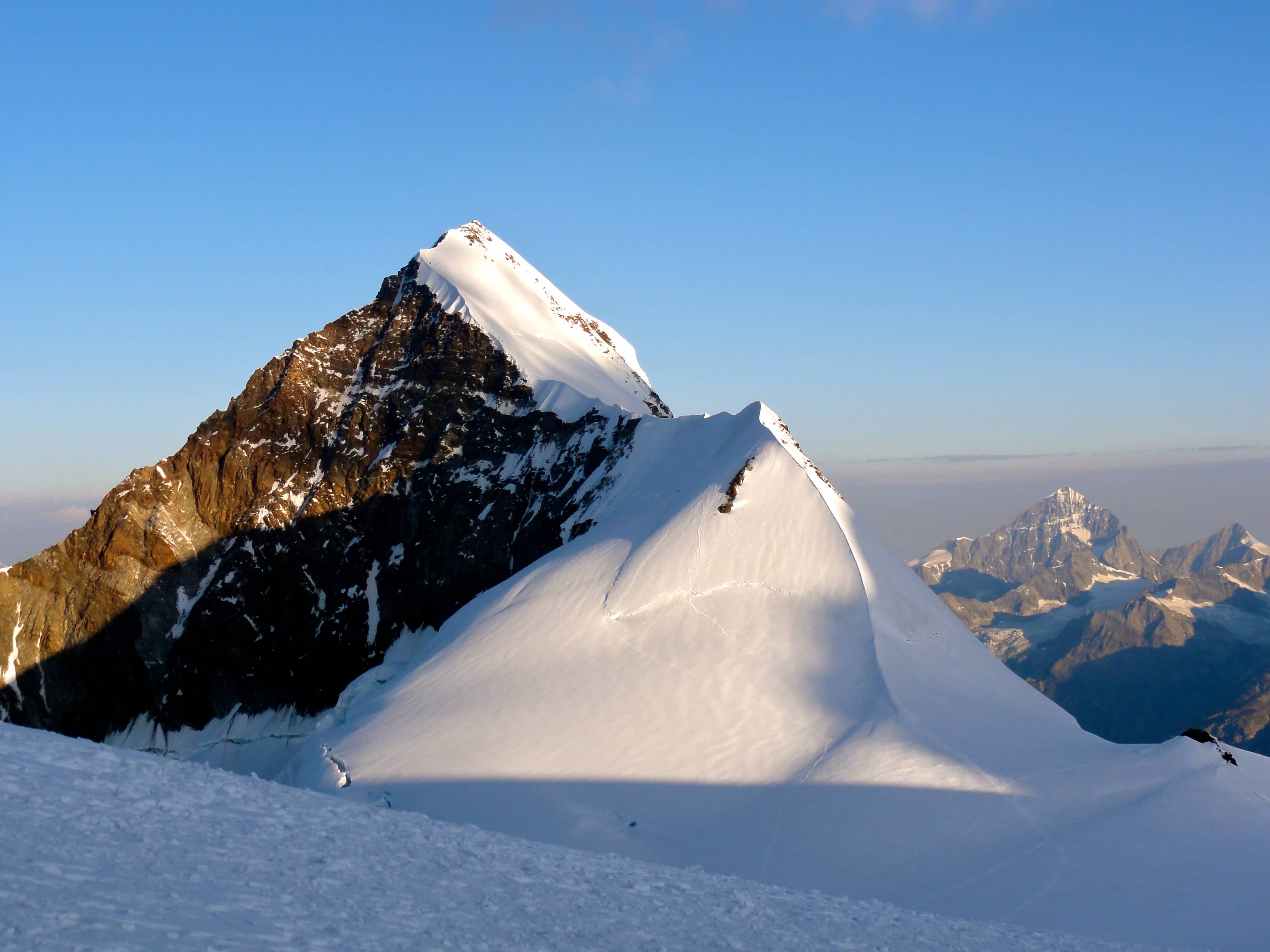 Der wunderschöne Liskamm Ostgipfel. Vom Lisjoch führt eine Spur direkt auf dem Grat hoch. Zwei weitere Spuren führen durch die sonnenbeschienene Flanke hoch zum Grat.